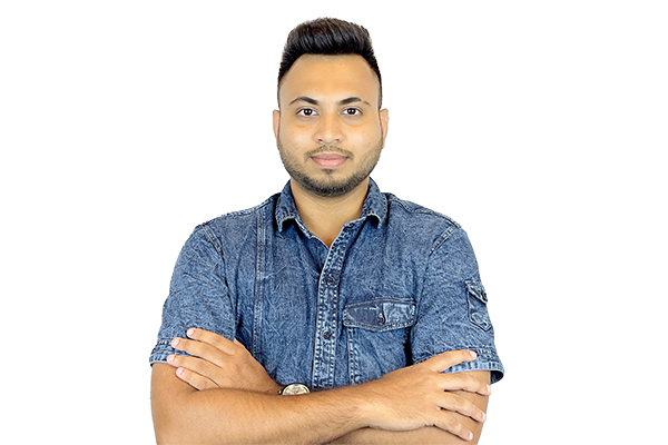 Man with short dark hair and beard, wearing a denim shirt, standing with arms crossed against a light background.